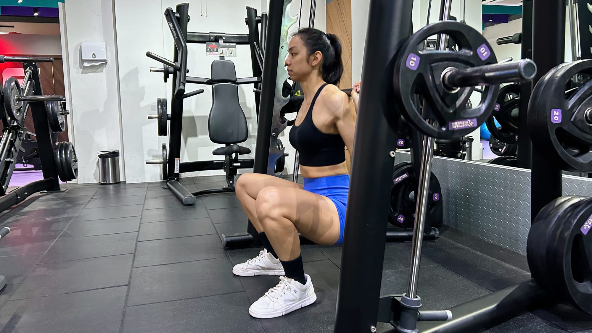 Sideview of Smith machine squat with feet in front of the bar